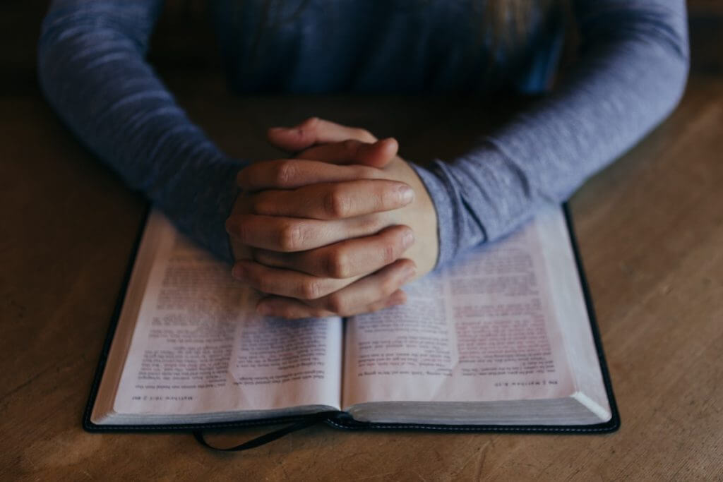 Praying hands on a Bible